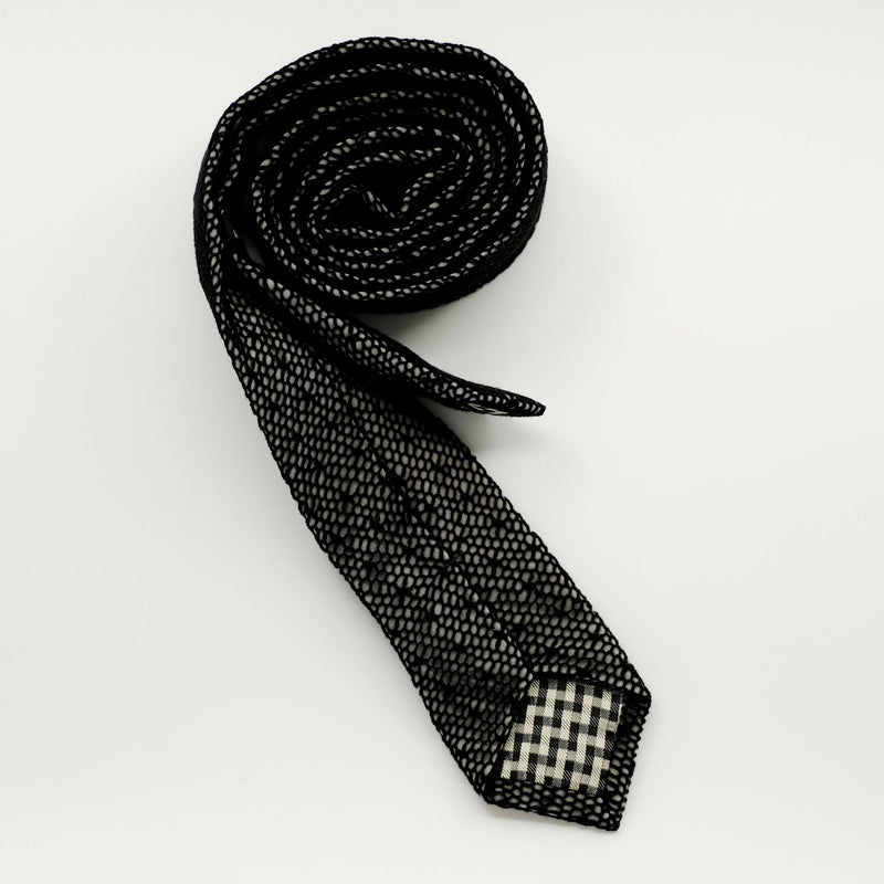 Black patterned tie on a light gray background
